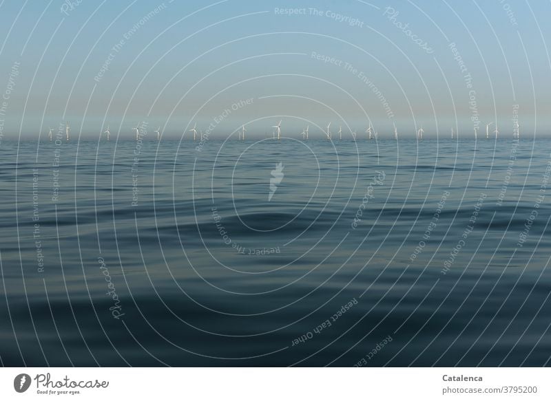 Das blaue Meer im Vordergrund, am Horizont ein Offshore-Windpark Weiß Energie Energiewirtschaft Blau Windrad Wasser erneuerbare Energie Windkraft nachhaltig