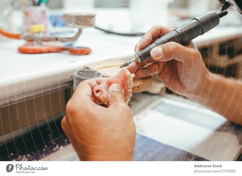 Crop Mann mit Maschine Polieren künstliche Kiefer Zahnersatz dental Techniker Zähne polnisch Prothesen männlich Arbeit Labor professionell Werkzeug Beruf Gerät