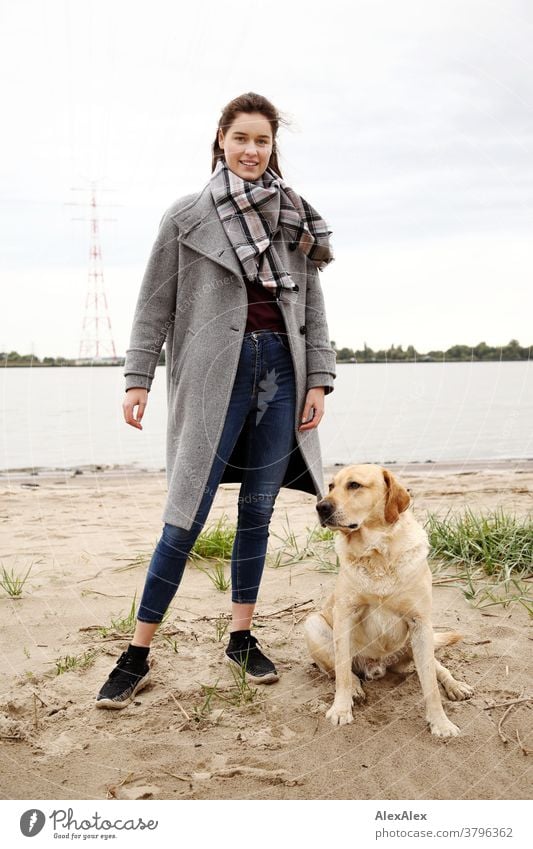 Nahes Portrait einer jungen Frau am Elbstrand mit blondem Labrador junge Frau 18-25 Jahre warmherzig schön charmant schlank brünett lange Haare frisch groß