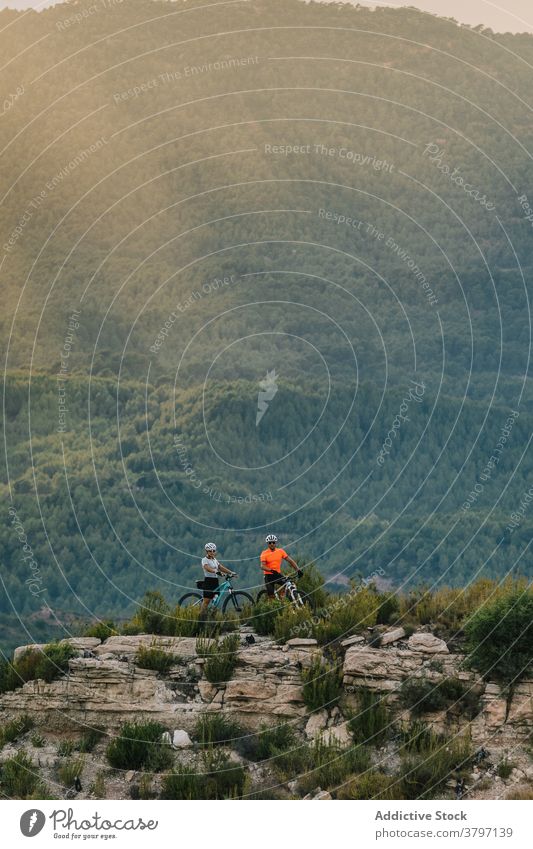 Fröhliche Radfahrer stehen auf einem Hügel in den Bergen Paar Zusammensein Berge u. Gebirge Sport Schutzhelm professionell Fahrrad sich[Akk] entspannen Pause