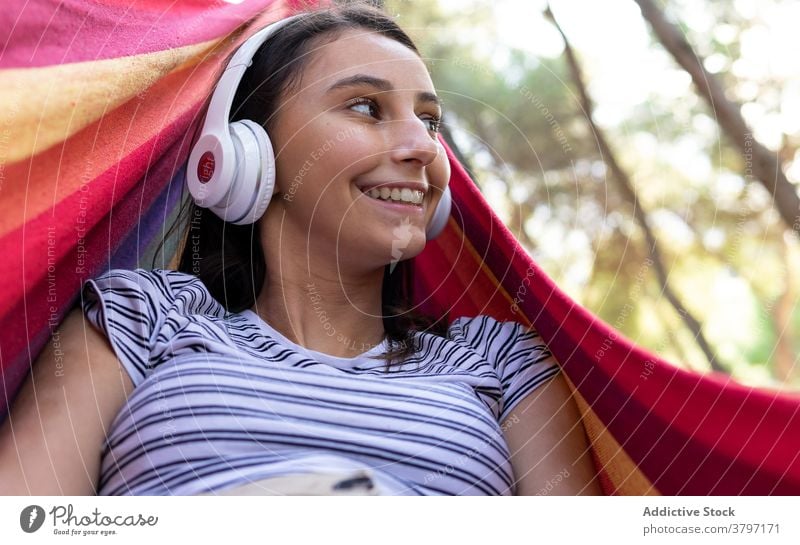 Sorglose Frau hört Musik in der Hängematte zuhören genießen hängen Park Drahtlos Melodie Windstille Kopfhörer friedlich Klang Lügen Gelassenheit Gesang Harmonie