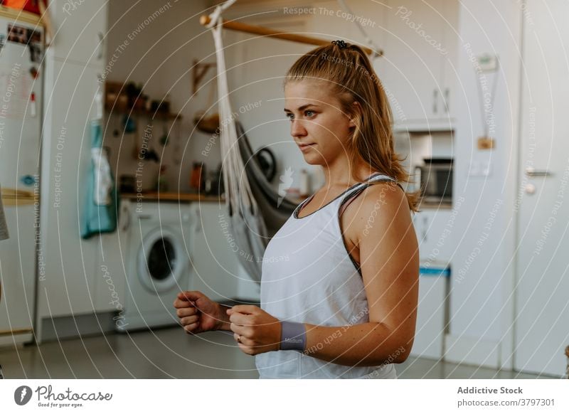 Frau mit Widerstand Band auf Handgelenke arbeiten zu Hause Sportlerin Übung Widerstandsband Training Vitalität Energie üben Aktivität physisch Sportbekleidung