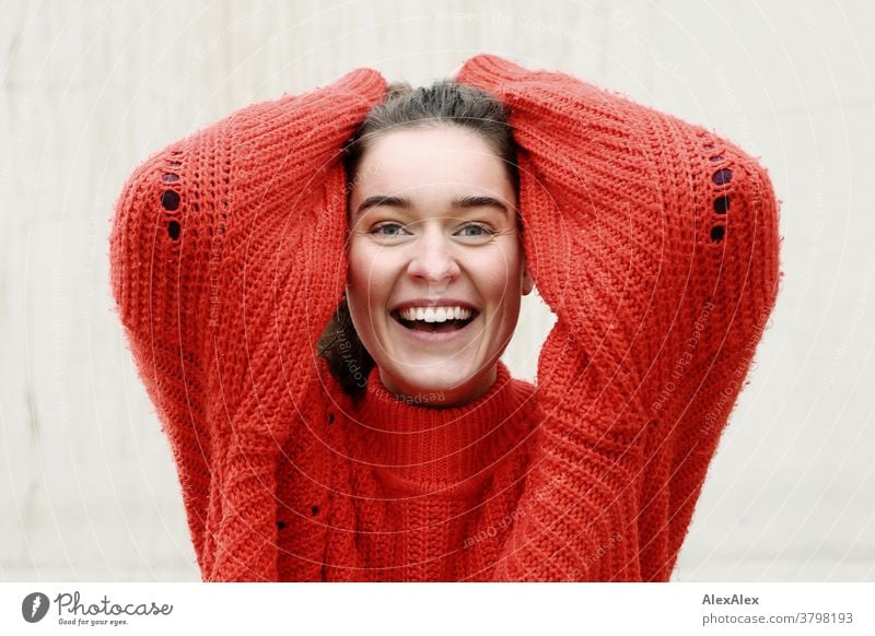 Nahes Portrait einer lachenden, jungen Frau mit Grübchen vor einer Betonwand junge Frau 18-25 Jahre warmherzig schön charmant schlank brünett lange Haare frisch