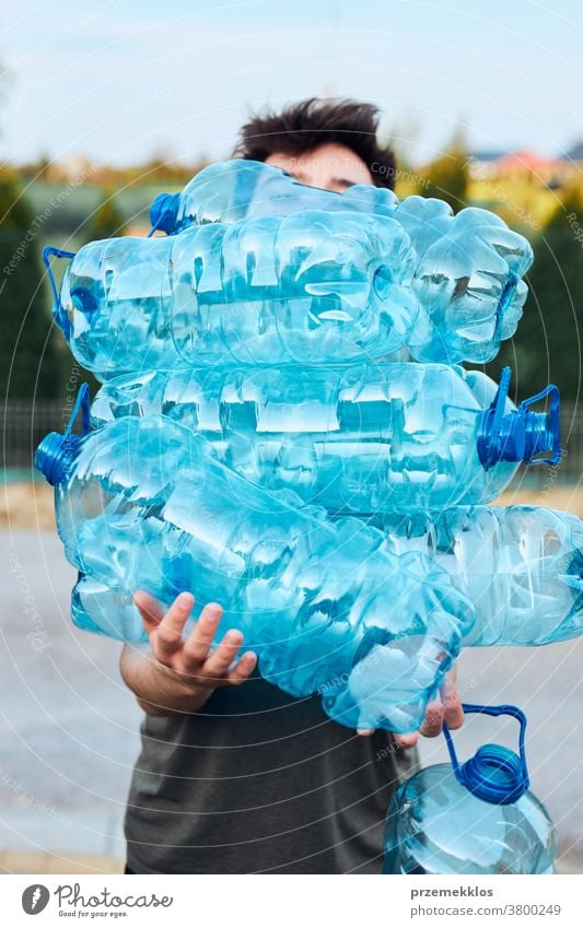 Junger Mann wirft leere gebrauchte Plastik-Wasserflaschen in den Mülleimer Behälter blau Flasche abholen sammelnd Container zerdrückt Entsorgung Ökologie Umwelt