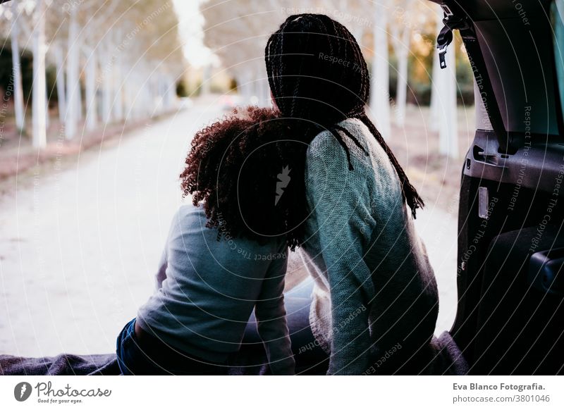 hispanische Mutter und Afrokindermädchen sitzen in einem Auto in der Natur. Herbstsaison. Familien- und Reisekonzept Porträt Tochter im Freien gemischte Rasse