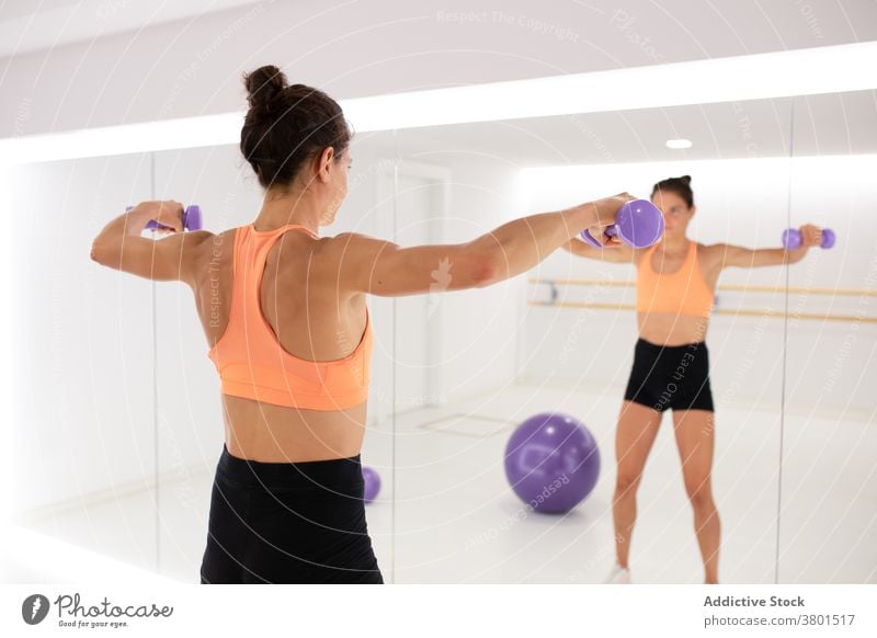 Unkenntlicher Sportler mit Hanteln, die sich beim Training im Spiegel spiegeln Sportlerin Übung Kurzhantel reflektieren Fitness Sporthalle Ball Gerät