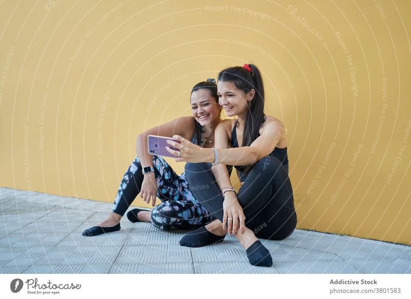 Positive Frauen sitzen auf dem Boden und nehmen Selfie auf Smartphone Inhalt positiv Apparatur Freund heiter benutzend Moment Stock modern jung Mobile Telefon