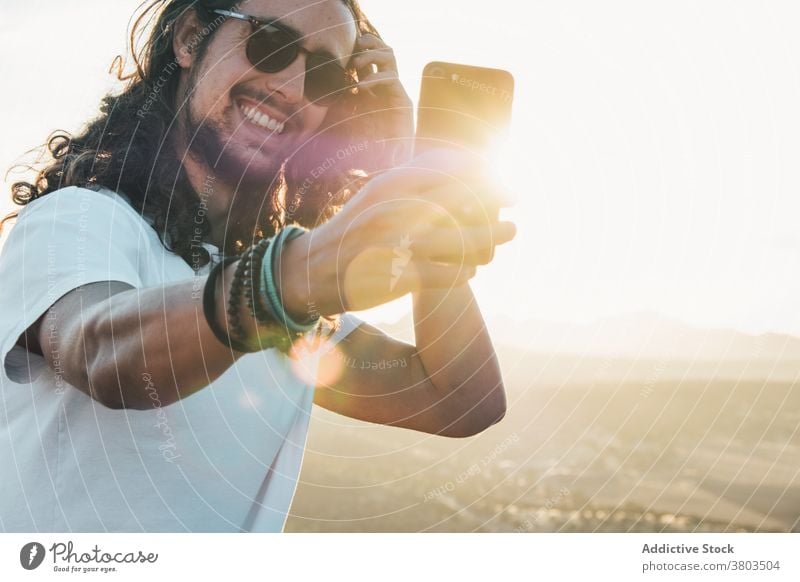 Fröhlich Mann unter Selfie gegen sonnigen üppigen Tal Reisender heiter Zahnfarbenes Lächeln Smartphone Natur aufgeregt Moment Apparatur Bergkuppe Fernweh reisen