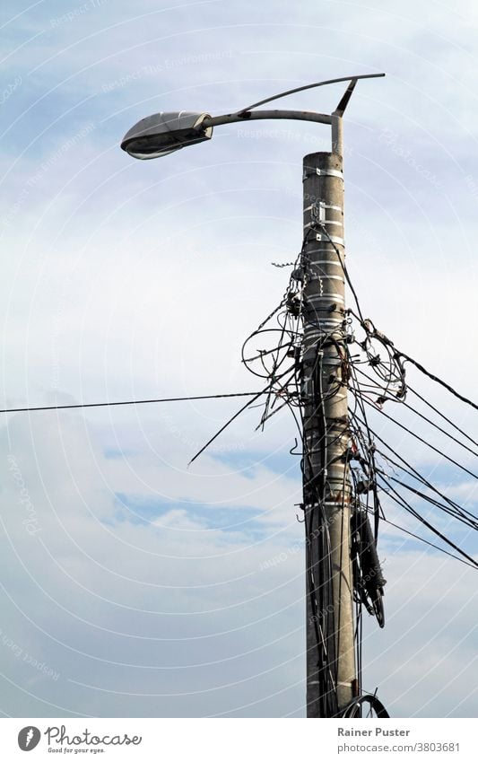 Verschlungene Stromleitungen an einer Straßenlaterne in Rumänien blau Kabel chaotisch Gefahr elektrisch Elektrizität Energie verstrickt Verstrickung Gerät hoch