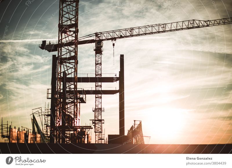 Baustelle, Silhouetten von Bauindustriearbeitern auf Gerüsten gegen das Licht der untergehenden Sonne. Kräne Kranich Arbeit Arbeitnehmer lenken Wehen