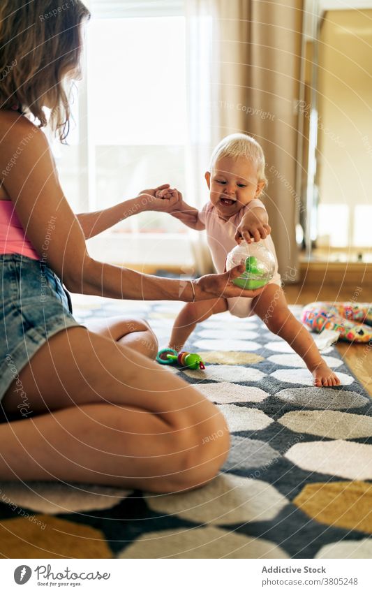 Fröhliche Mutter und Baby Mädchen spielen auf dem Boden Frau Stock heimwärts Glück Spaß haben Spielzeug Grimasse Liebe Tochter Zusammensein bezaubernd jung Kind