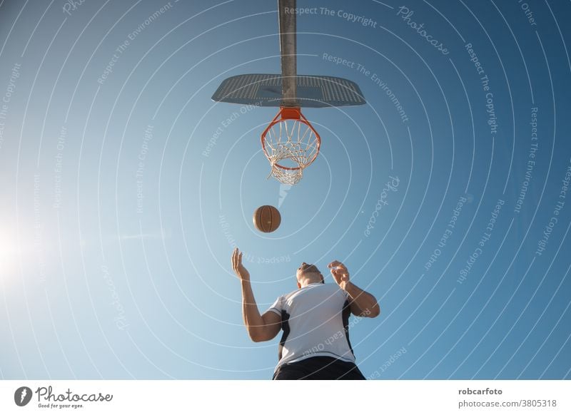 Mann, der auf der Straße auf einem Außenplatz Basketball spielt. Spaß Sport urban Menschen cool Männer Ball Schuss jung Spiel männlich Erwachsener Gericht