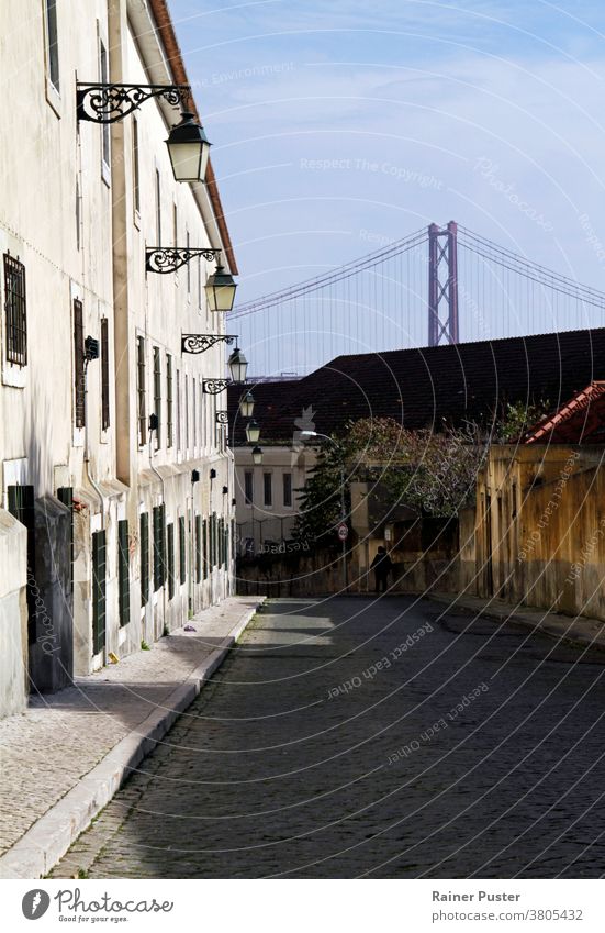 Die berühmte Brücke Ponte 25 de Abril in Lissabon, Portugal, im Hintergrund einer ruhigen Straße Stadtbild ruhige Straße blau Gebäude Wahrzeichen Landschaft