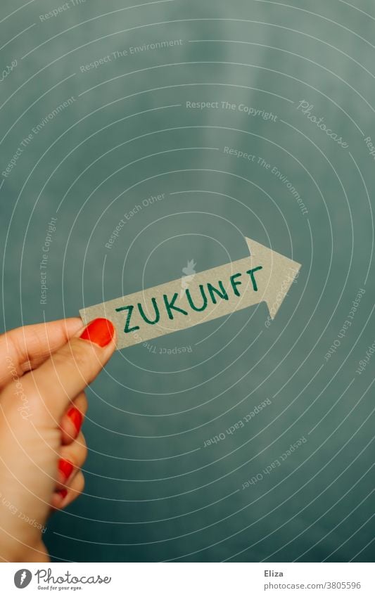 Hand einer Frau hält einen grünen Pfeil mit der Aufschrift Zukunft weiblich Ziel Erfolg Karriere Planung Zukunftsorientiert Optimismus Richtung Business