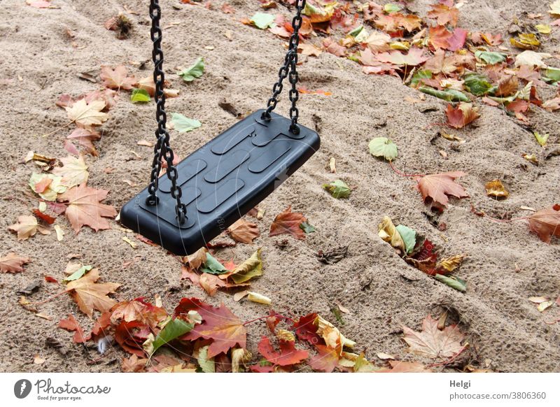 Herbststimmung auf dem Spielplatz - Schaukel hängt über regennassem Sandboden, der mit Herbstblättern bedeckt ist Schatten Blätter Ahornblatt Herbstfärbung