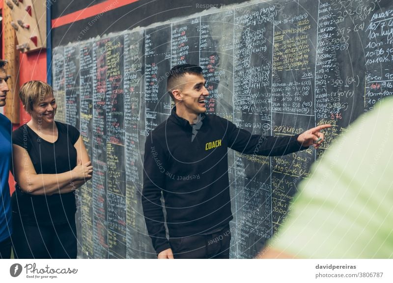 Der Trainer erklärt den Athleten in der Turnhalle zu erklären. Ergebnisse Lachen Spaß genießend Training Tafel Ausbilderin Fitnessstudio durchkreuzen passen