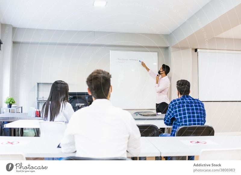 Anonymer Manager unterrichtet Kollegen in der Nähe der Markertafel im Klassenzimmer erklären Projekt Mitarbeiterin lehren zeigen Markierung Holzplatte