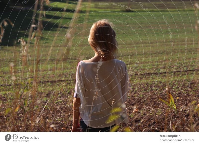 Mädchen schaut auf einen frisch grünen Acker Frühjahr Wachstum warten Ackerboden Rückenansicht Feld Landschaft schauen Ackerbau Landwirtschaft Frühling