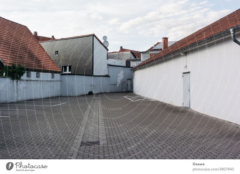 Leerer Parkplatz im Hinterhof eines Gewerbe- / Wohngebiets Rückseite Gebäude Häuser Stadt städtisch Pflaster Menschenleer Verwaist Fassade Wand Mauer Dächer