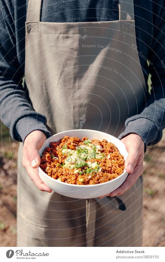 Kropfenkoch mit Schüssel mit schmackhaftem Hackfleisch auf dem Lande zerkleinern Fleisch ländlich Koch Mann Speise vorbereiten lecker Schürze