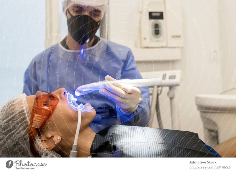 Zahnarzt behandelt Zähne eines Patienten mit UV-Licht ultraviolett Gerät Zahnmedizin Kur Stomatologie Werkzeug dental professionell Klinik Medizin mündlich