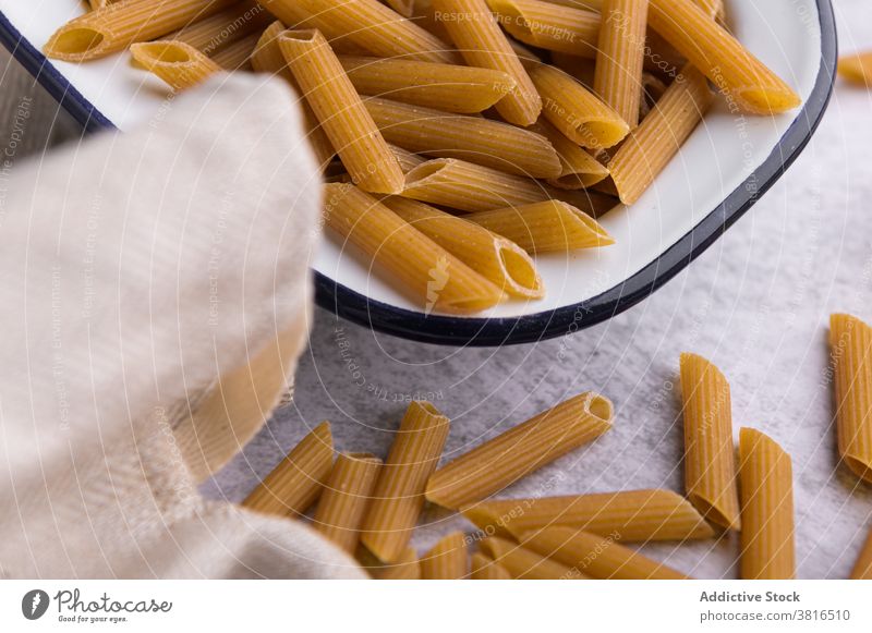 Trockene Nudeln in Schüssel und auf Tisch in Küche Spätzle trocknen Penne getrocknet Makkaroni Erdöl oliv Flasche Ordnung Italienische Küche Metall