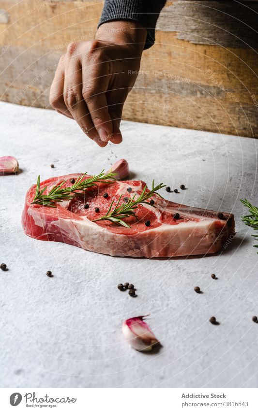 Kropfenkoch, der das Steak am Knochen würzt Rindfleisch t Knochen roh Küchenchef Gewürz hinzufügen bestäuben appetitlich lecker Koch Fleisch Mahlzeit