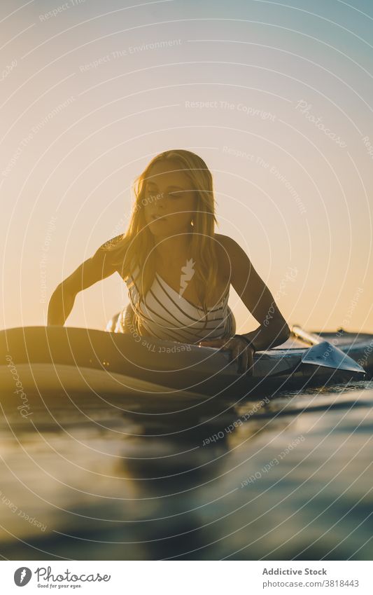 Gelassene Frau auf Surfbrett im Meer Lügen MEER sich[Akk] entspannen Sonnenuntergang schlank Badeanzug Wasser winken Himmel Erholung Sommer Badebekleidung ruhen