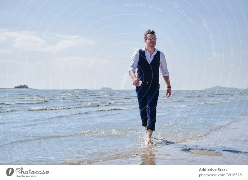 Fröhlicher Geschäftsmann im Anzug hat Spaß auf wellenförmigen Ozean Spaß haben Meer stylisch Outfit sorgenfrei wellig Blauer Himmel wolkig Wasser Bekleidung