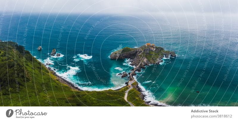 Gekräuseltes Meer in der Nähe von grünen Berg mit Gehweg unter Himmel Berge u. Gebirge Gaztelugatxe Natur Hochland San Juan Meereslandschaft Atmosphäre Laufsteg