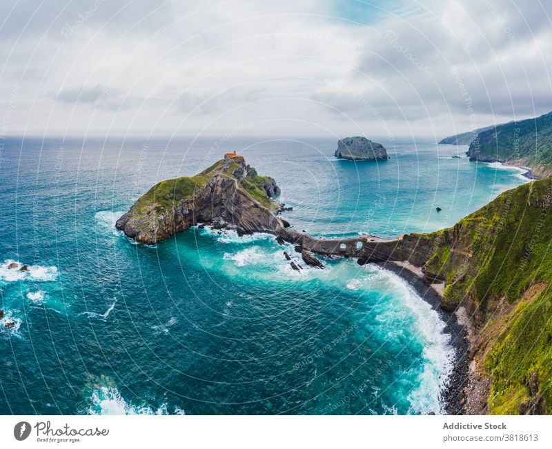 Gekräuseltes Meer in der Nähe von grünen Berg mit Gehweg unter Himmel Berge u. Gebirge Gaztelugatxe Natur Hochland San Juan Meereslandschaft Atmosphäre Laufsteg