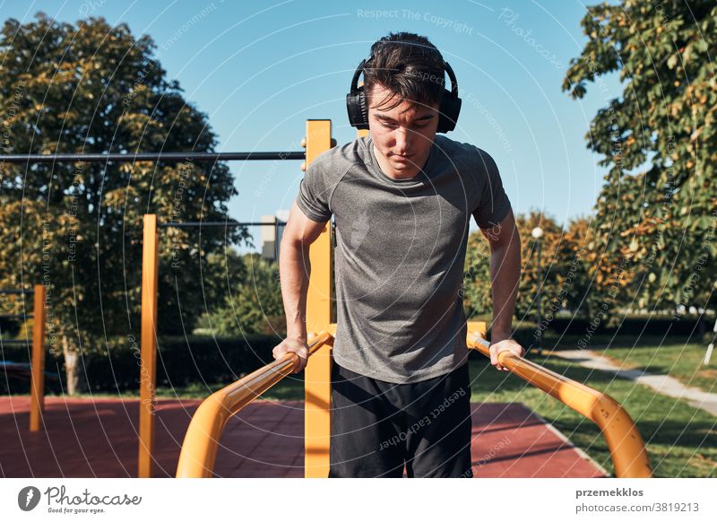 Junger Mann, der während seines Trainings in einem modernen Gymnastikpark auf parallelen Stangen baden geht calisthenics Pflege Kaukasier Gesundheit Lifestyle