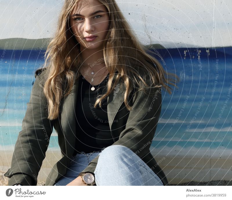 Blondes Mädchen sitzt an einer Wand mit Graffiti Landschaft Strand intensiv jugendlich freundlich Natur weiblich einzigartig außergewöhnlich natürliches Licht