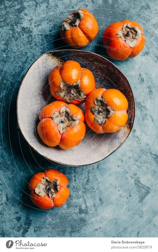 Köstliche Kakipflaume in einem Teller auf blauem Hintergrund süß frisch saftig Gesundheit orange Lebensmittel organisch Diät reif Vegetarier Frucht Ernährung