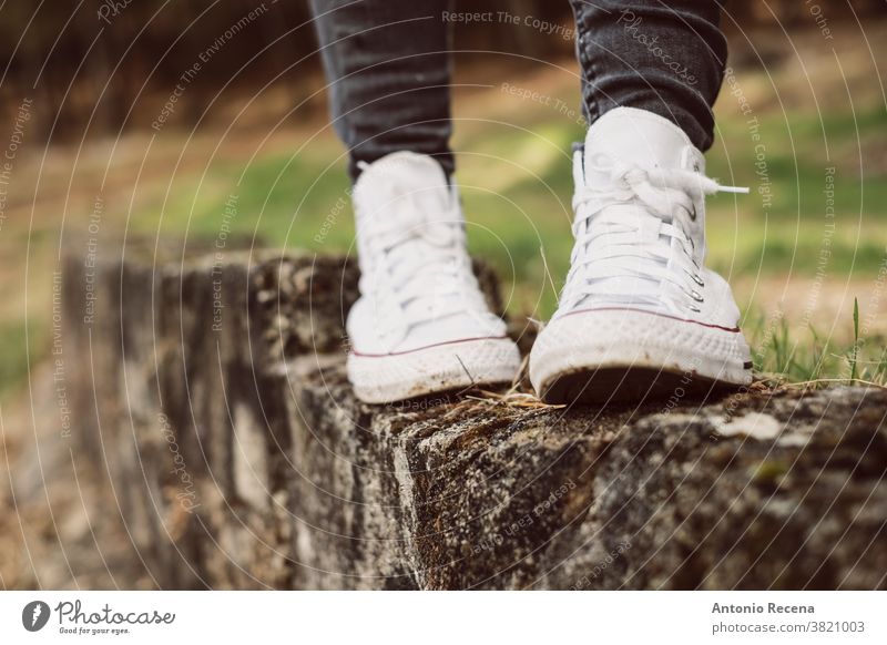 Füße in weißen Turnschuhen, die im Freien auf einer Wand balancieren Fuß laufen snickers Schuh Schuhe Gleichgewicht Beine Frau Wald Abtrennung anonym