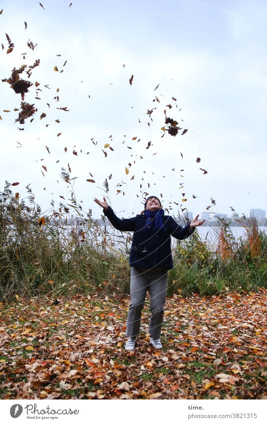 Flugmodus Frau Herbst Spaß Laub werfen Herbstlaub wiese horizont skyline stehen freude fliegen himmel jacke böschung schilf ufer seeufer