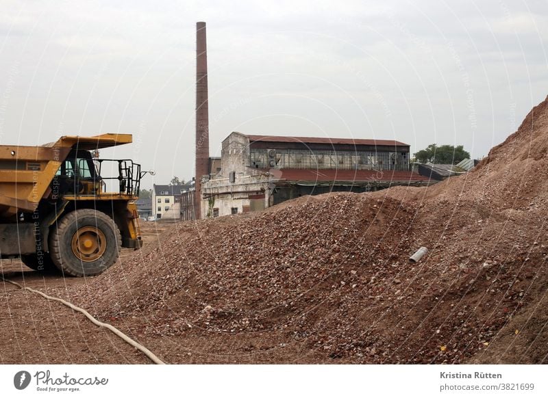 abrissarbeiten auf ehemaligem fabrikgelände großbaustelle fabrikhalle schornstein schuttberg bauschutt schotter material baustoff steine wiederverwertung hügel