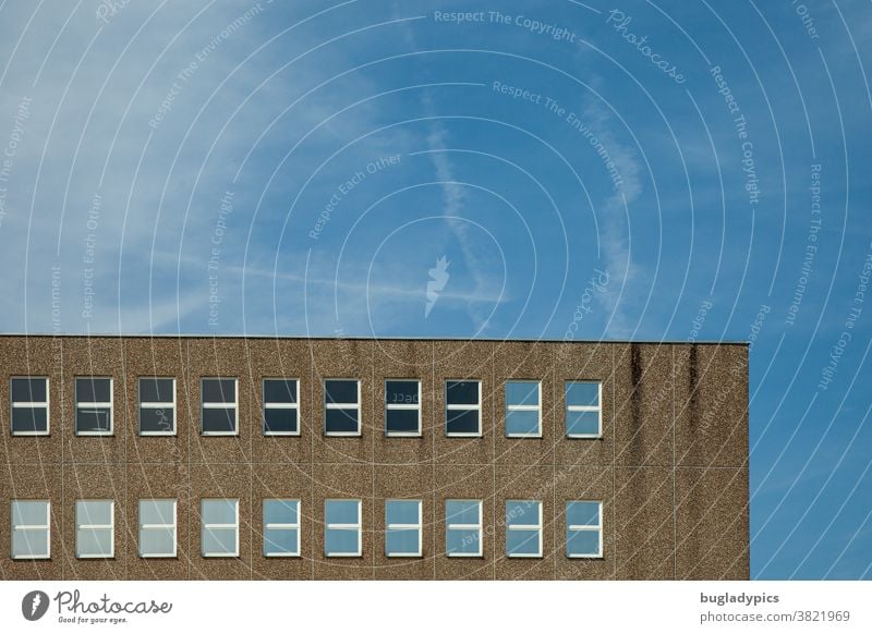 Gebäude aus Waschbeton mit vielen Fenstern vor blauem Himmel mit Wolken und Kondensstreifen Architektur Haus Beton Glasfenster Fassade Bauwerk grau trist