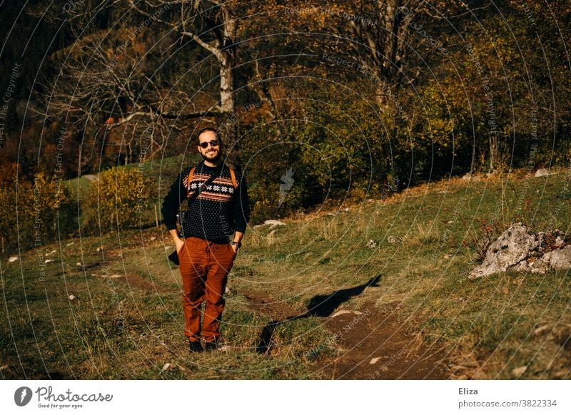 Ein junger Mann steht in einer herbstlichen Landschaft und lächelt Natur Herbst Ausflug Wandern Sonnenschein goldener Herbst Schönes Wetter Wald Wiese