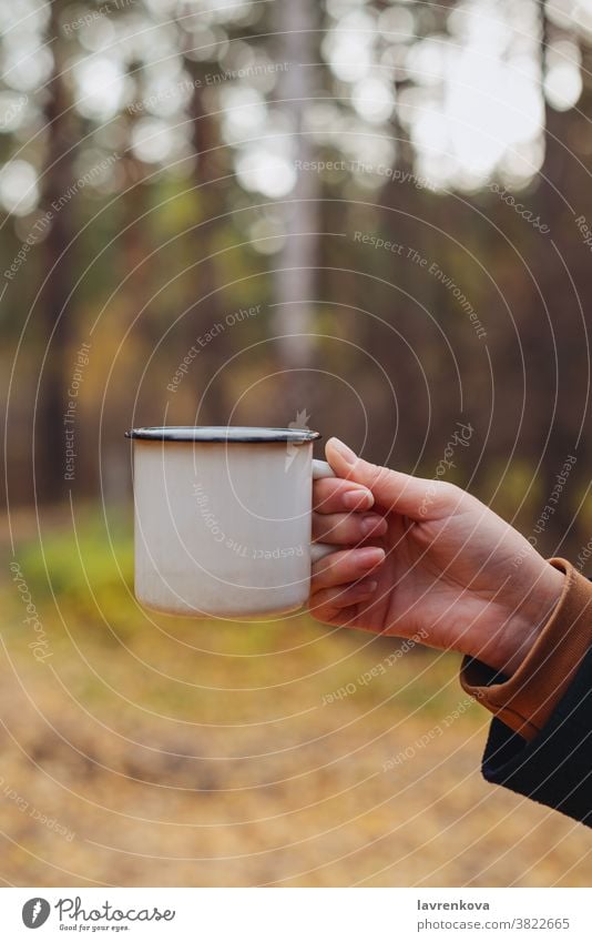 Weibliche Hand hält Emaillebecher mit warmem Getränk im Wald trinken Becher Tee Kaffee im Freien Herbst fallen Tasse Freizeit kalt Lifestyle reisen Abenteuer