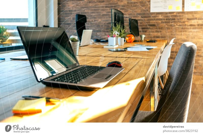 Interieur eines Coworking-Büros im Industriestil leer Laptop industrieller Stil Arbeitsplatz Schreibtisch Tisch informell Backsteinwand Computer Fenster Raum