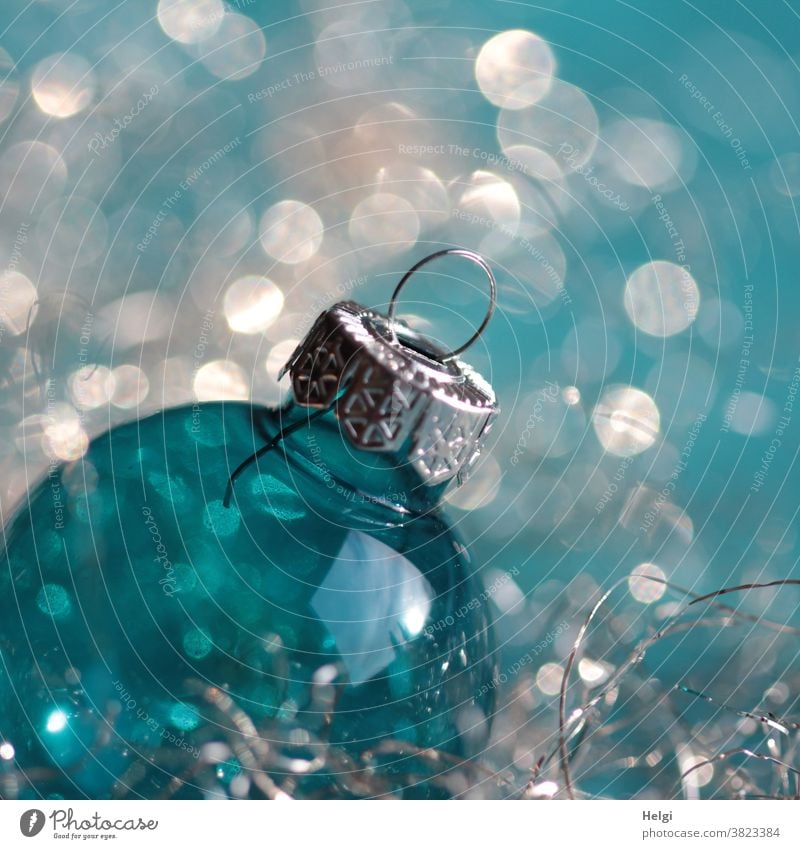 Weihnachtsglitzern - türkisblaue Weihnachtskugel aus Glas mit silbernem Aufhänger vor türkis-weißem Hintergrund mit Bokeh Glaskugel Dekoration Weihnachtsschmuck