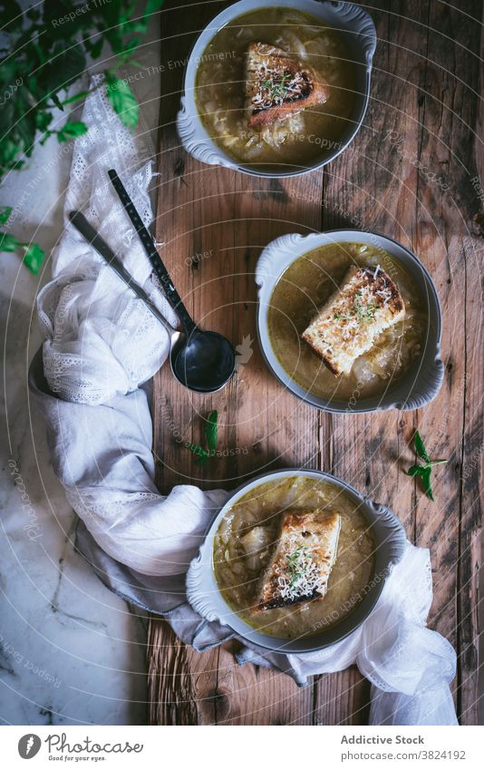 Schüssel mit französischer Zwiebelsuppe auf Holzunterlage Rahmsuppe Suppe Gemüse Schalen & Schüsseln Brot Küche Lebensmittel foodcollection Kräuter veggies