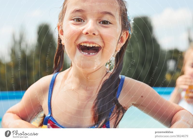 Porträt eines glücklich lächelnden Mädchens, das an einem sonnigen Sommertag in einem Schwimmbad steht und sich amüsiert authentisch Hinterhof Kindheit Kinder