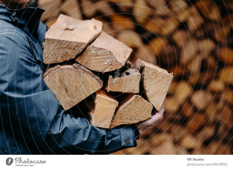 Unbekannter Mann trägt mit Jacke bekleidet einen Haufen Holz zum Feuermachen. Gesichtsloser Mann trägt Brennholz ins Haus hölzern männlich im Freien Totholz