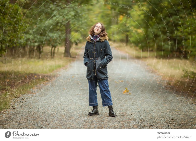 Ein Mädchen steht im Walde... und genießt die herbstlich würzige Luft Teenager Jugendliche verträumt lächelnd heiter Herbst Park Waldweg Bäume entspannt