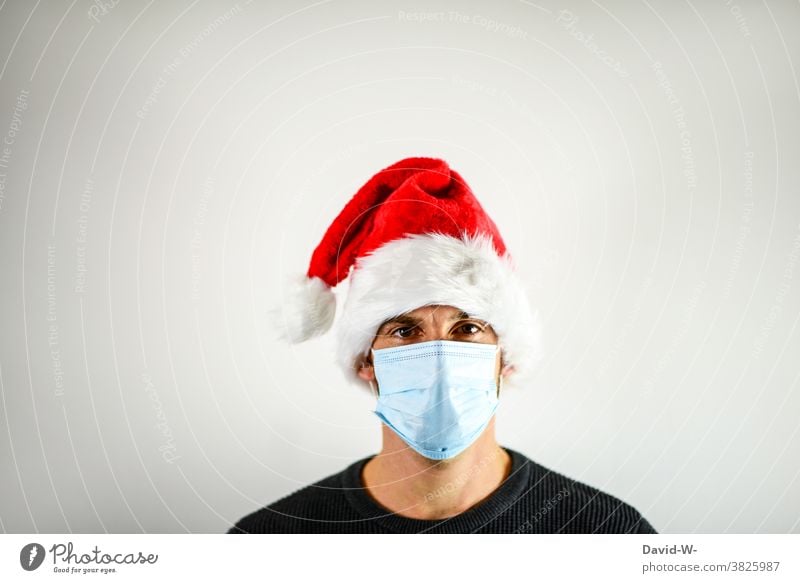 Corona und Weihnachten - Mann mit Atemschutzmaske und Nikolausmütze Mundschutz adventszeit Maske Pandemie Coronavirus Infektionsgefahr Schutz Gesundheit