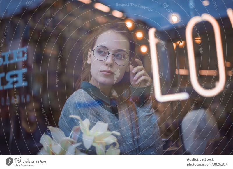 Gelassene Frau in stilvoller Kleidung im Café sich[Akk] entspannen Abend gemütlich Atmosphäre verträumt jung Stil Kaffeehaus trendy Outfit lässig Fenster