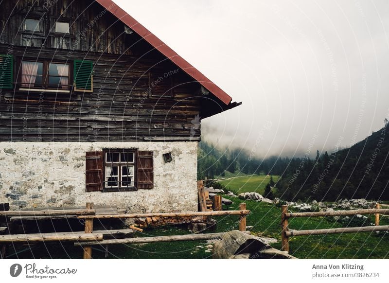 Berghütte Berge Wandern Bayern Hütte Haus Alm urig Holz Holzfenster Zaun Wiese Alpen Pause einkehren Wolken Nebel fensterläden alt heruntergekommen Wald