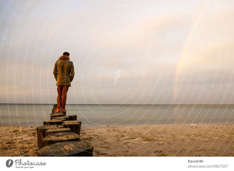 Mann steht auf Pfählen die ins Meer gehen und bewundert den Regenbogen Nordsee Ferne Küste ruhe Strand Ferien & Urlaub & Reisen Wasser Himmel Insel wunderschön